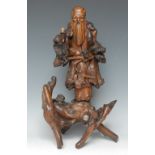 A 19th century Chinese rootwood carving, of an immortal holding a ripe peach,