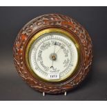 An Edwardian mahogany circular aneroid wall barometer, carved with acorns and oak leaves,