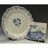 A Dutch Delft tile, decorated in cobalt blue with figures by a river, before a church,