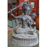 A bronzed metal Buddha, seated in lotus position, wielding a sword,