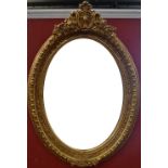 A large and elaborate oval gilt framed mirror, bevelled glass,