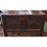 A 17th century oak blanket chest, three panel hinged top above a profusely carved front,