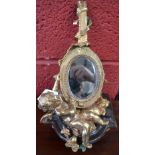 A gilt metal mantel mirror, cherub supporting lyre, on stepped marble base,