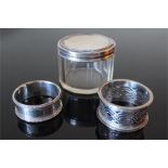 A cut-out silver napkin ring W.A Birmingham, a silver lidded multi faceted class jar and another