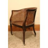 An early 19th century Mahogany Bergere Tub chair with turned front legs and outswept rear on