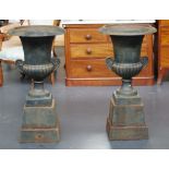 Pair of cast iron garden urns on stands