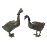 A pair of life-sized bronze geese: both standing, one looking upward, 53cm and 67cm. high.