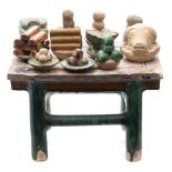 A Chinese votive earthernware table laden with plates of food: including a boar's head, eggs, fruit,
