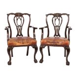 A pair of carved mahogany elbow chairs in the Chippendale taste:,