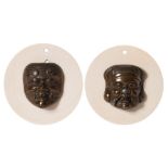 A pair of Japanese bronze Noh masks: mounted on circular ivory mounts, each mask 5cm.