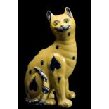 A Mosanic pottery cat: modelled seated and painted with blue circle and heart motifs on a yellow