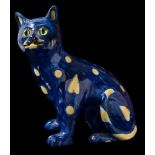 A pottery cat, probably Mosanic: modelled in seated posture with inset green glass eyes,