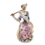 A Bow figure of a seated lady flautist: wearing a yellow cloak,