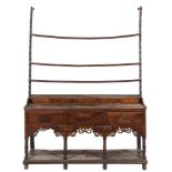 An 18th Century oak dresser:, the shelved superstructure with a shaped apron canopy,