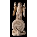 A Japanese carved ivory okimono of a child standing on a drum: wearing traditional robes,