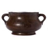 A Chinese bronze censer: of squat circular form, with loop handles to the side, on a circular foot,