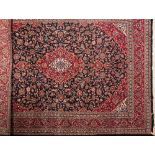 A Kashan carpet:, the indigo cartouche field with a central red cartouche pole medallion,