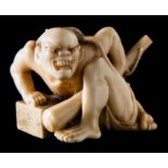 A Japanese carved ivory okimono of a rat catcher: crouching and holding a kanabo,