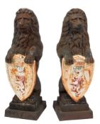 A pair of painted cast iron lions sejant : holding shields bearing a rampant lion below a crown,