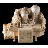 A Japanese carved ivory okimono: of a teacher and pupil at a table learning to write the alphabet,