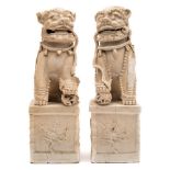 A pair of Chinese porcelain Lion Dogs: each seated with one paw resting on a pierced brocade ball,