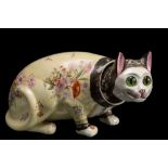 A Galle-style 'nodding' pottery cat: modelled crouching and transfer decorated with flowers on a