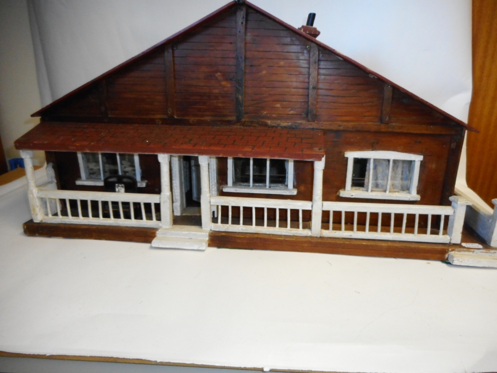 A ski lodge style dolls house: with three ground floor rooms below a pitched roof and veranda, 68cm.
