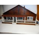 A ski lodge style dolls house: with three ground floor rooms below a pitched roof and veranda, 68cm.