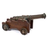 A brass and mahogany model of a cannon on a Royal Navy pattern truck with iron wheels:, 46cm long.
