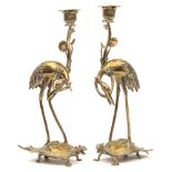 A pair of Chinese brass candlesticks: modelled in the form of cranes riding on the backs of turtles,