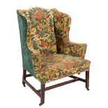 A George III mahogany wing frame armchair:, fully upholstered in floral foliate tapestry,