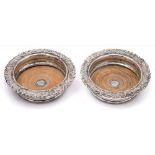 A pair of plated wine coasters: of circular form with scroll and foliate borders,