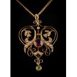 An Edwardian 9ct gold garnet, peridot and seed pearl pendant: of open scroll design,