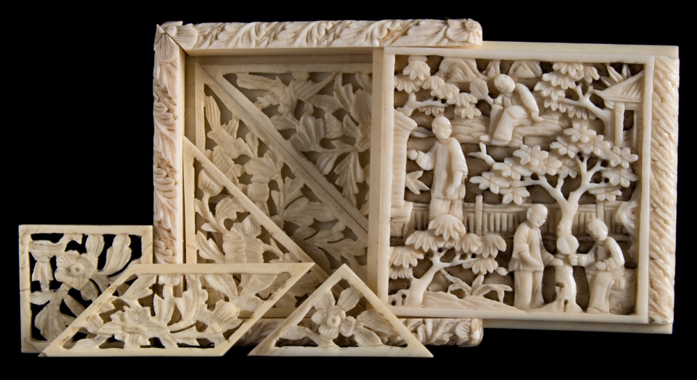 A 19th century Chinese carved ivory tangram puzzle: of square outline with sliding cover carved