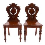 A pair of Victorian carved mahogany hall chairs:,