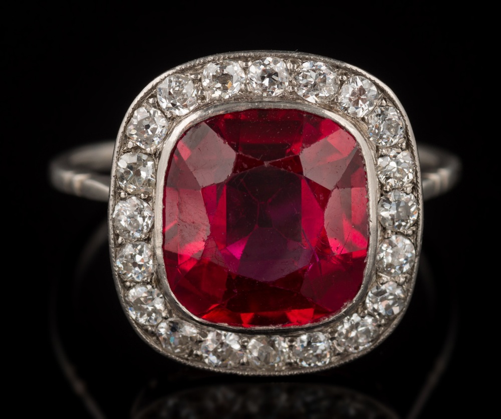 A synthetic ruby and diamond cushion shaped cluster ring: the synthetic ruby approximately 11.