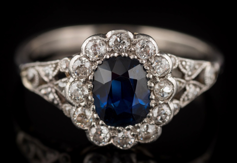 A sapphire and diamond oval cluster ring: the oval sapphire approximately 6mm long x 4.8mm wide x 2.