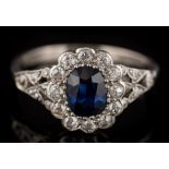 A sapphire and diamond oval cluster ring: the oval sapphire approximately 6mm long x 4.8mm wide x 2.