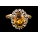A chrysoberyl and diamond oval cluster ring: with central oval yellow chrysoberyl claw-set within a