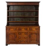 A late 18th Century oak dresser:, the shelved superstructure with a moulded cornice,