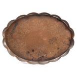 A Newlyn copper tray: of oval outline with wavy edge border,