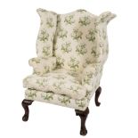 A stained beech frame wing armchair:, of shaped outline in the George III manner,