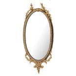 A 19th Century gilt gesso and ebonised oval mirror:, with tied laurel leaf cresting,