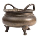 A Chinese bronze tripod censer: the compressed globular body with waisted neck and loop handles,