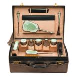 A George V green leather travelling vanity case: containing silver and green enamel mounted jars,