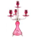 A cranberry and clear glass candelabra: the bulbous waisted base on three feet supporting a central