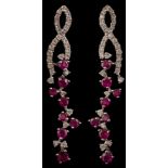 A pair of modern ruby and diamond pendant earrings: with stylised openwork ribbons suspending