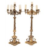 A pair of gilt metal five-light candelabra: with urn-shaped nozzles on scrolling arms,