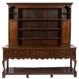 An 18th Century and later oak dresser: the later shelved superstructure with a moulded cornice and