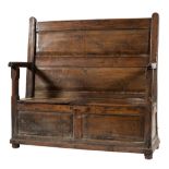 An early 18th century oak box settle: with a fielded twin panel back and twin panelled hinged seat